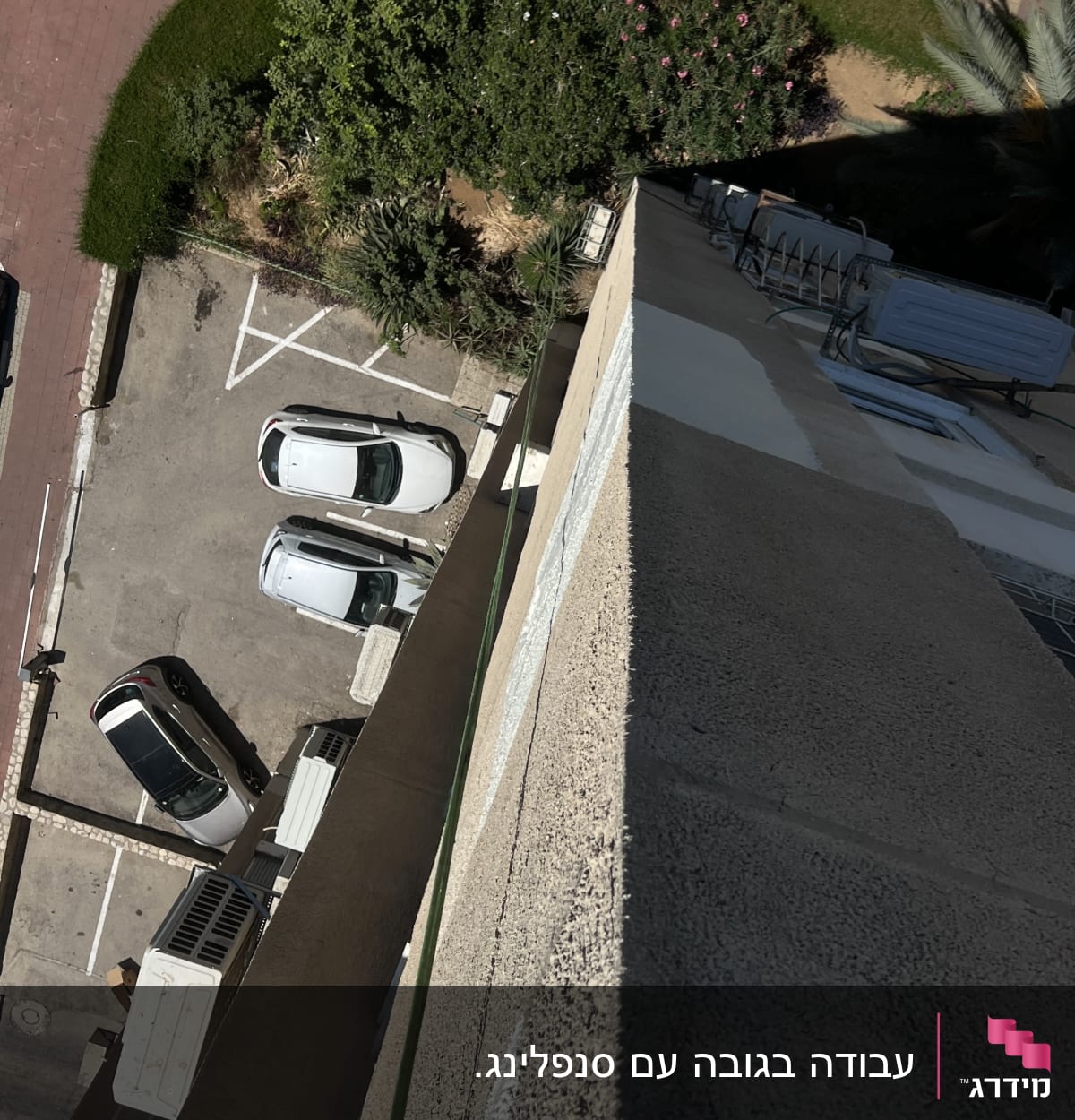 מבט מלמעלה על חניה ומדרכה ליד בניין גבוה